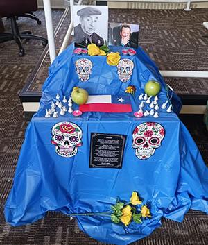 Blude day of the dead ofrenda with candy skulls chocolate, apples, photographs and yellow roses, and Texas flag
